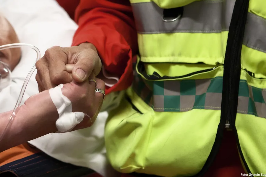 Foto av helsepersonell som holder hånden til en pasient om bord i en luftambulanse