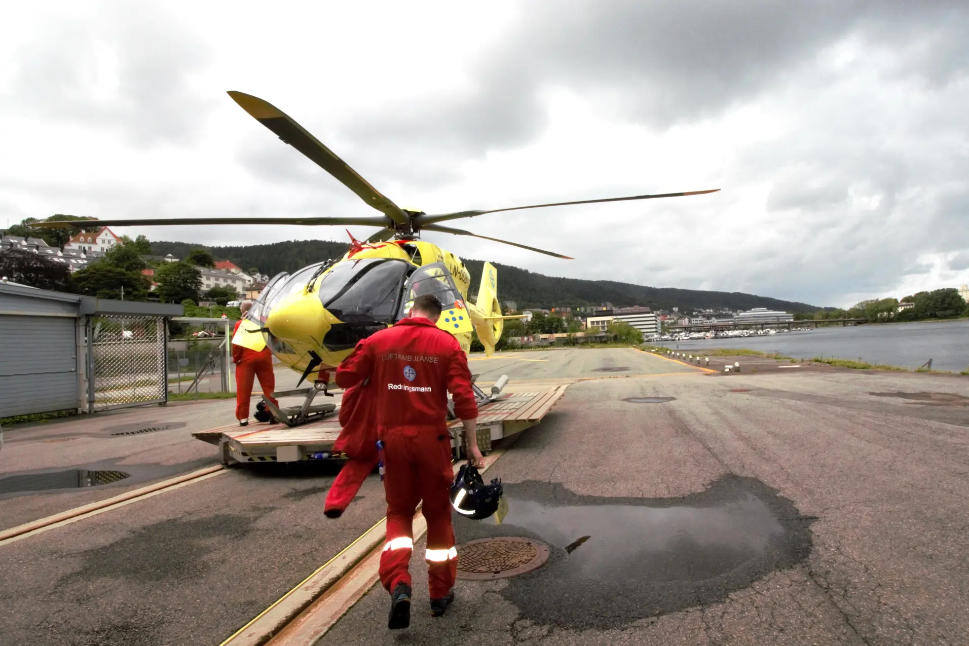 En person i rød jumpsuit ved et helikopter