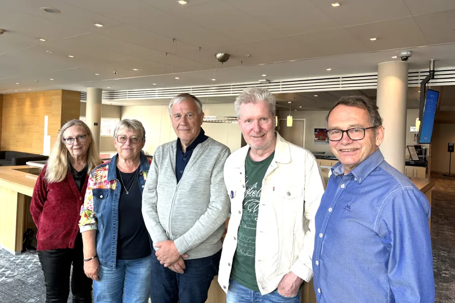 To kvinner og tre menn står sammen.